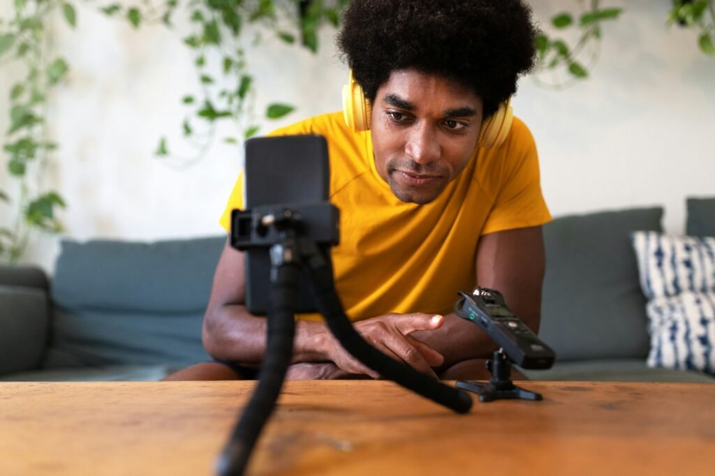 Young african american man recording himself for social media network checking the recorder.